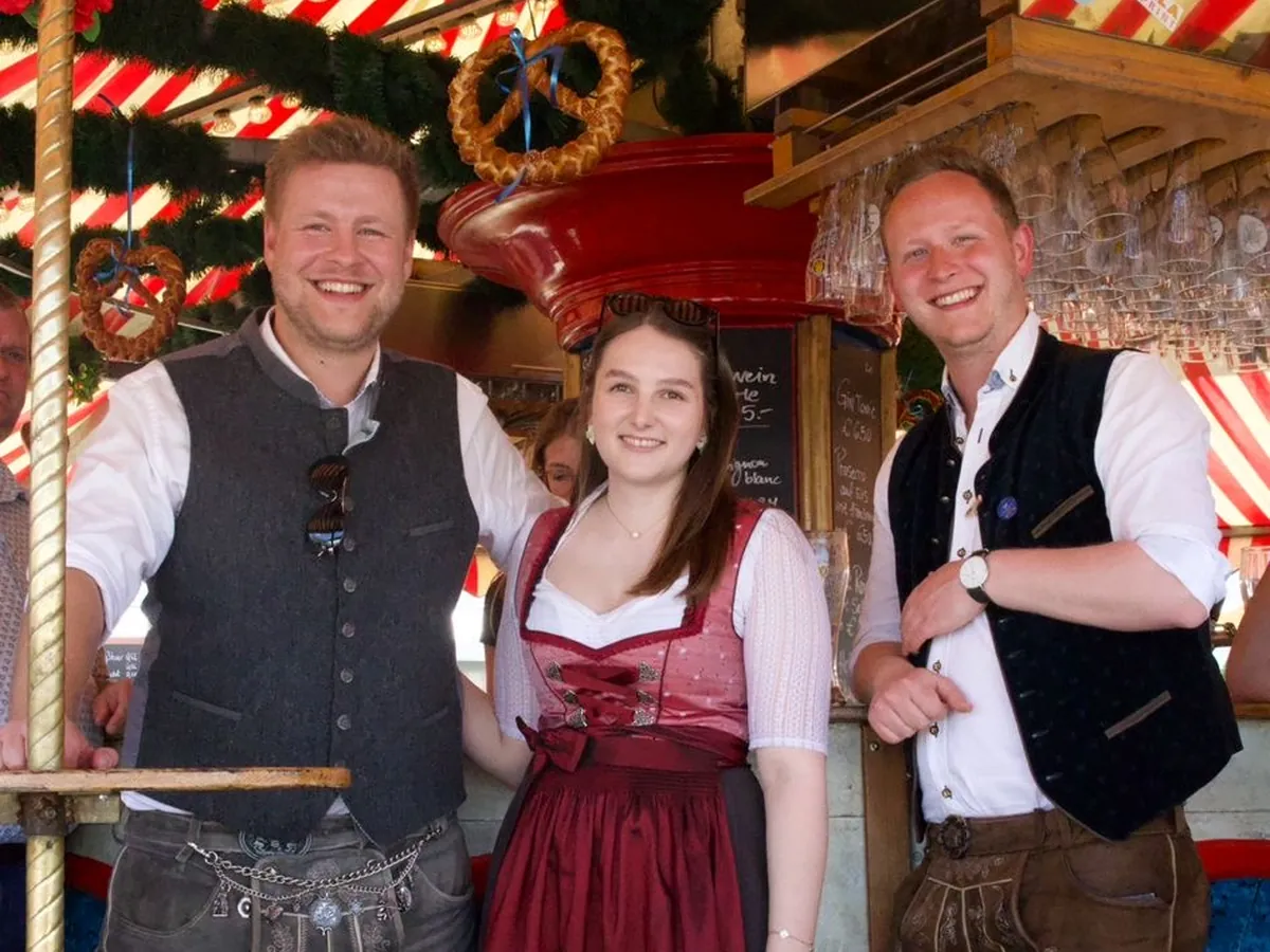 Drei junge Leute auf dem Karussell, in der Mitte ein Dirndl