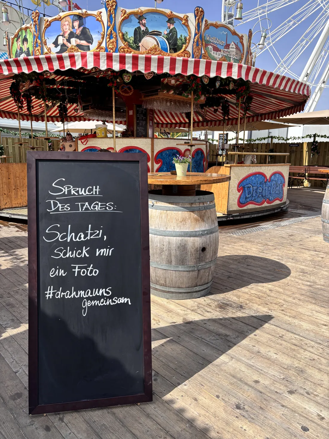 Weißbiergarten am Karussell mit Tafel „Spruch des Tages“ und #drahmaunsmidanand