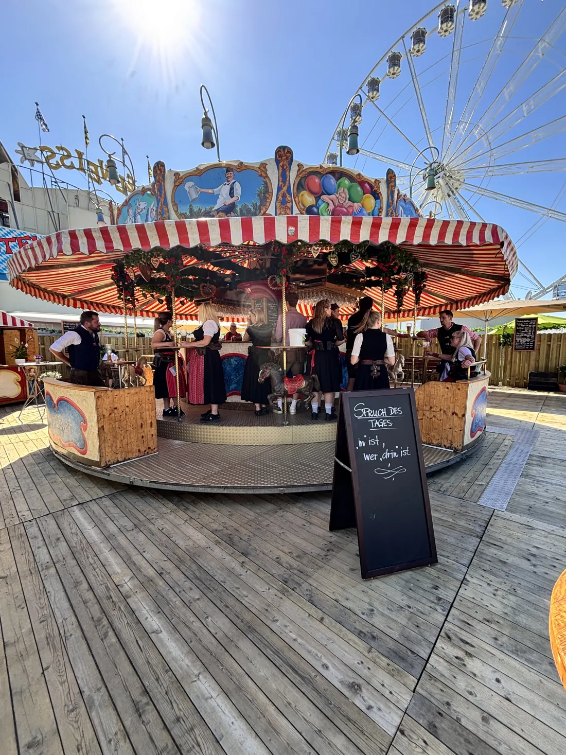 Das Weißbierkarussell mit rot-weißem Dach vor dem Riesenrad auf der Passauer Dult